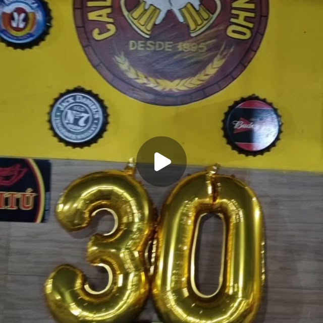 Balões dourados de 30 anos em frente à parede com a logo do Caldinho Amarelinho