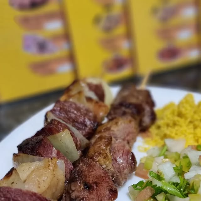 Espetinhos de carne servidos com farofa e vinagrete